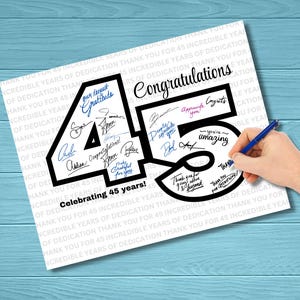 Può includere: Un biglietto bianco con la parola "Congratulazioni" e il numero "45" in nero. Il numero è pieno di firme e frasi come "La nostra più profonda gratitudine" e "Festeggiamo 45 anni!" Una mano con una penna blu sta scrivendo sulla carta.