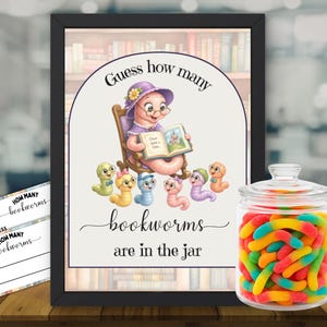 Puede incluir: Un letrero enmarcado con el texto Guess how many bookworms are in the jar que muestra una ilustración de un gusano con sombrero morado leyendo a gusanos más pequeños, junto a un frasco de vidrio transparente con gominolas y dos tarjetas.