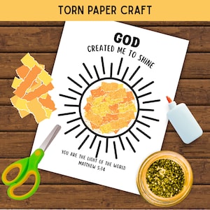 May include: A torn paper craft activity sheet featuring a sun illustration with the text GOD CREATED ME TO SHINE and YOU ARE THE LIGHT OF THE WORLD MATTHEW 5:14. Includes yellow and orange paper scraps, green scissors, glue, and gold glitter.