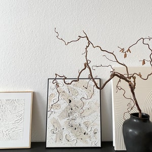 以下が含まれることがあります： 白い背景に白と黒の塗料で描かれた抽象画が3つ額装されています。絵画の前に、枯れ枝が入った花瓶があります。