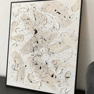 以下が含まれることがあります： 白のキャンバスに黒と白の塗料で描かれた抽象画。塗料は、はね、線、渦巻きなど、さまざまなテクスチャで塗られています。