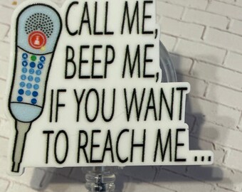 May include: A badge reel featuring a light blue communicator graphic with a keypad and a red button, accompanied by the black text "CALL ME, BEEP ME, IF YOU WANT TO REACH ME..." on a white background, attached to a clear plastic retractable clip.