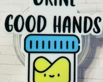 May include: A badge reel featuring a white acrylic topper with the black text "URINE GOOD HANDS" above a graphic of a specimen container with a blue lid and a yellow liquid interior that has a small, simple smiling face printed on it.