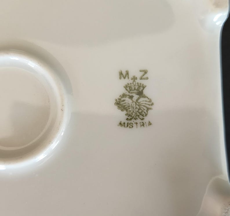 May include: Close-up of a white ceramic plate with a green mark that reads "M+Z" and "AUSTRIA".