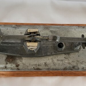 Peut inclure: Une balance &agrave; &oelig;ufs vintage en m&eacute;tal avec une base en bois. La balance a un anneau circulaire sur le c&ocirc;t&eacute; gauche et un levier sur le c&ocirc;t&eacute; droit. La balance est &eacute;tiquet&eacute;e "Reliable Egg Scale" et "See Weight Chart".