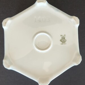 May include: White porcelain hexagonal base with a green mark that reads "M.Z. Austria" and the number "1403" printed on the top.
