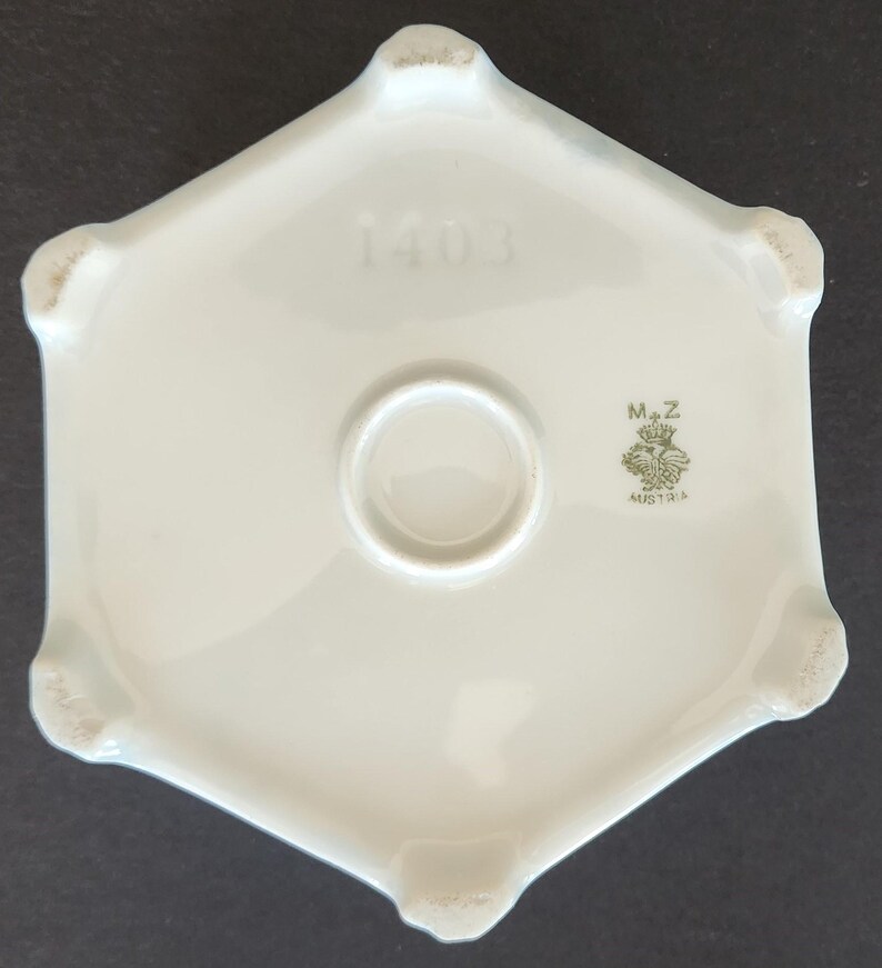 May include: White porcelain hexagonal base with a green mark that reads "M.Z. Austria" and the number "1403" printed on the top.