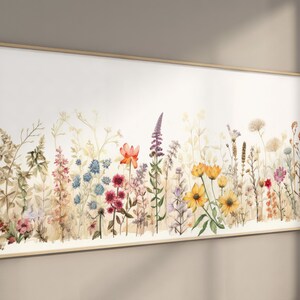 Puede incluir: Una pintura de acuarela de un campo de flores silvestres en tonos de rojo, naranja, amarillo, azul y morado. Las flores están dispuestas en una línea horizontal a través del lienzo, con un fondo blanco.