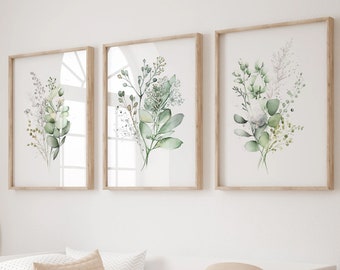 May include: Three framed watercolor prints of green botanical illustrations with white backgrounds. The prints are hanging on a white wall above a white daybed with a beige quilt and pillows.