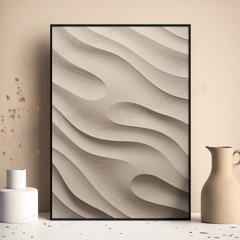 May include: A framed abstract print with a beige background and a wavy, textured pattern. The print is in a black frame and is hanging on a beige wall.