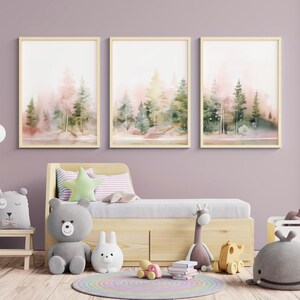 Op de afbeelding: Drie aquarellen van een boslandschap in roze en groene tinten. De schilderijen zijn ingelijst in licht hout en hangen aan een lichtpaarse muur. De schilderijen hangen boven een licht houten bed met een wit-roze gestreept kussen en een groen stervormig kussen.