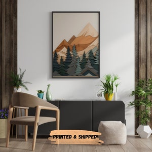 May include: A framed print of a mountain landscape with a layered wood effect. The mountains are brown and orange, and the trees are green and blue. The print is in a black frame and is hanging on a white wall.