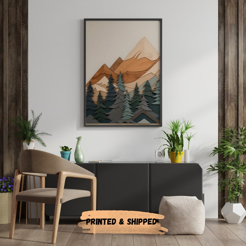 May include: A framed print of a mountain landscape with a layered wood effect. The mountains are brown and orange, and the trees are green and blue. The print is in a black frame and is hanging on a white wall.