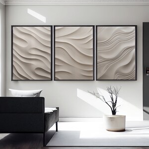 May include: Three framed abstract art prints with a white and gray wavy pattern. The prints are hanging on a white wall in a modern living room.