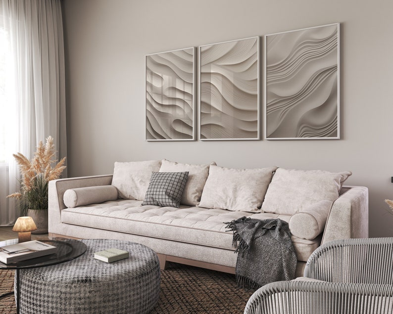 May include: A white sofa with a gray throw blanket and three pillows, one with a black and white checkered pattern. The sofa is in front of a wall with three framed abstract art prints with a wavy pattern in shades of gray.