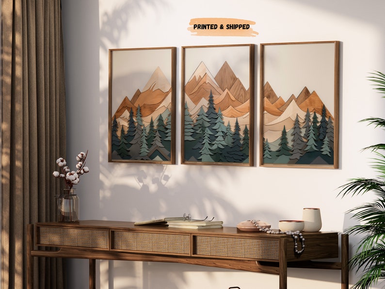 May include: Three framed prints of a layered wood art piece depicting a mountain range with a forest in the foreground. The mountains are in shades of brown, orange, and beige, while the trees are in shades of green and blue. The text "PRINTED & SHIPPED" is visible at the top of the image.
