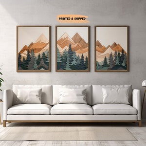May include: Three framed wood art prints with a layered mountain and forest scene. The mountains are in shades of brown and the trees are in shades of green and blue.
