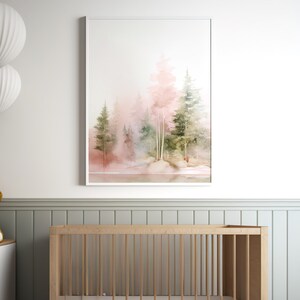 Op de afbeelding: Een aquarel schilderij van een bos sc&egrave;ne met roze en groene bomen. De bomen zijn gesilhouetteerd tegen een zachte roze en witte achtergrond. Het schilderij is ingelijst in een wit frame.