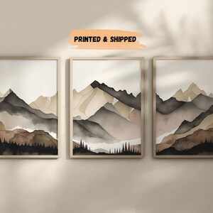 Peut inclure: Trois peintures &agrave; l'aquarelle encadr&eacute;es d'une cha&icirc;ne de montagnes dans des tons de brun, beige et gris. Les peintures sont dispos&eacute;es en rang&eacute;e sur un mur blanc.