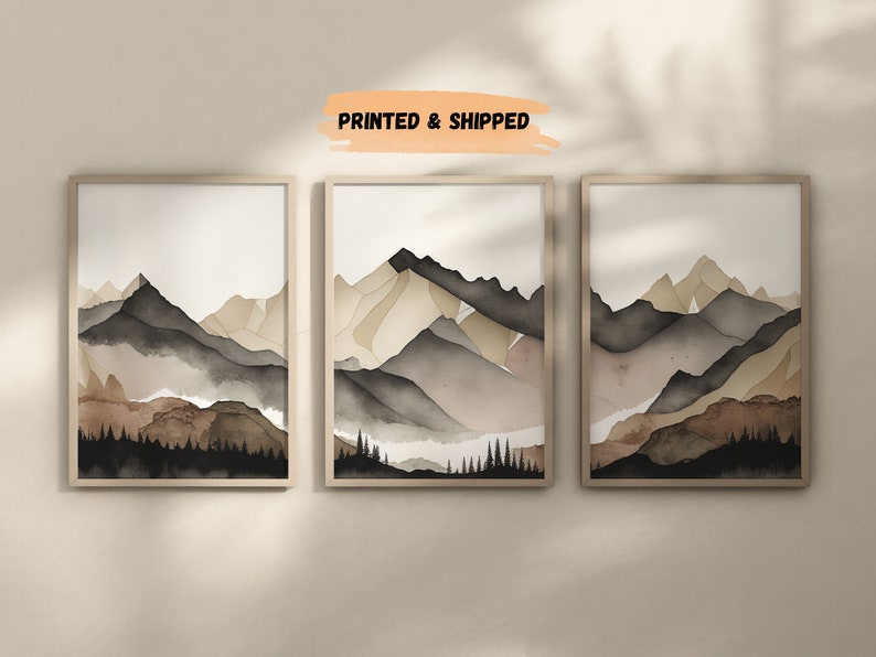 Peut inclure: Trois peintures &agrave; l'aquarelle encadr&eacute;es d'une cha&icirc;ne de montagnes dans des tons de brun, beige et gris. Les peintures sont dispos&eacute;es en rang&eacute;e sur un mur blanc.