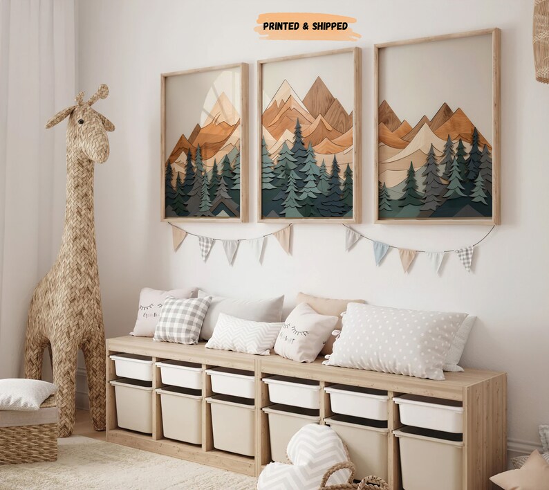 May include: Three framed wood art prints depicting a mountain range with a forest in the foreground. The prints are in shades of brown, green, and blue. The prints are hanging on a white wall above a wooden bench with white storage bins. The bench is decorated with pillows.