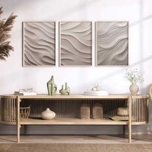May include: A light wood console table with a curved front and open shelves. The table has a woven basket, a vase with dried flowers, and three ceramic vases on the top shelf. Three framed abstract prints with a wavy pattern hang on the wall behind the table.