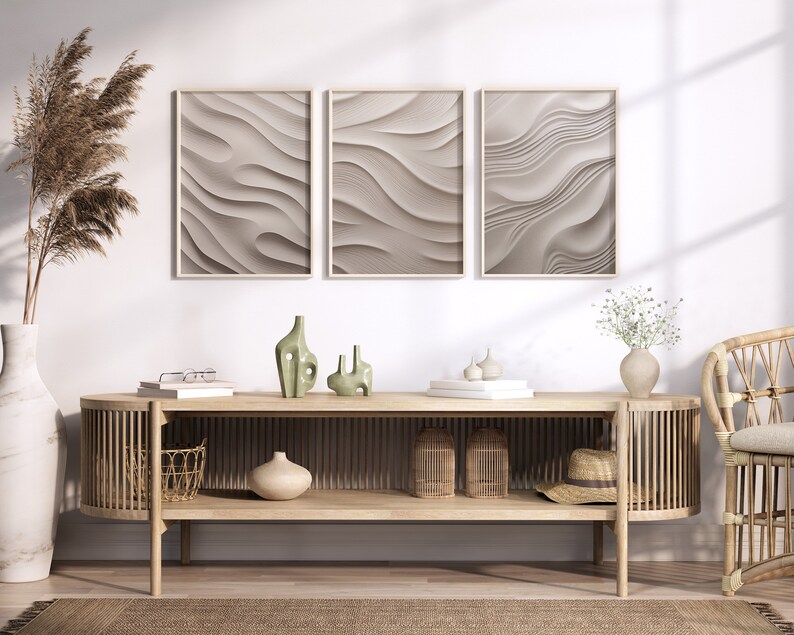 May include: A light wood console table with a curved front and open shelves. The table has a woven basket, a vase with dried flowers, and three ceramic vases on the top shelf. Three framed abstract prints with a wavy pattern hang on the wall behind the table.