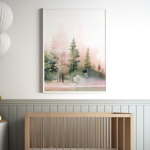 Op de afbeelding: Een aquarel schilderij van een bos sc&egrave;ne met hoge bomen en een roze en groene kleurstelling. Het schilderij is ingelijst in een wit frame en hangt aan een witte muur.