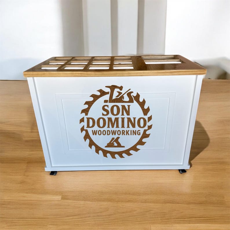 May include: A white wooden box with a brown wooden top and the text "SON DOMINO WOODWORKING" in a circular design. The box is rectangular and may be used for storage or display.