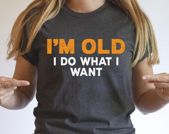 May include: A dark gray t-shirt with the text "I'M OLD I DO WHAT I WANT" in orange lettering.