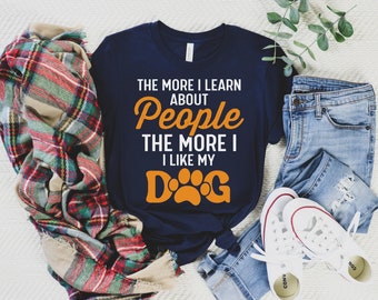 May include: A navy blue t-shirt with the text "The more I learn about people the more I like my" and a paw print with the word "Dog" in orange.