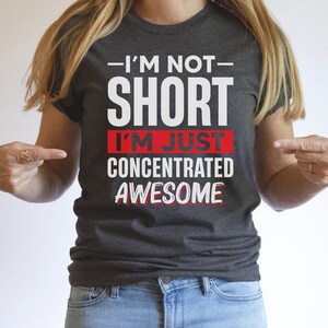May include: A dark gray t-shirt with white text that reads "I'm not short I'm just concentrated awesome" with the words "I'm just" in red.