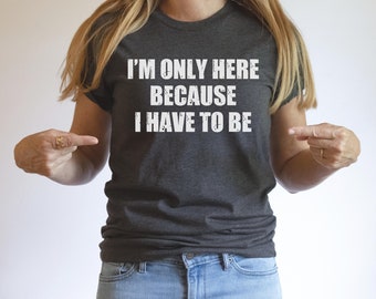 May include: A dark gray t-shirt with the text "I'm only here because I have to be" printed in white.