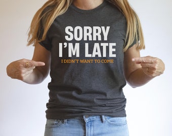 May include: A dark gray t-shirt with the text "Sorry I'm Late I didn't want to come" in white letters.
