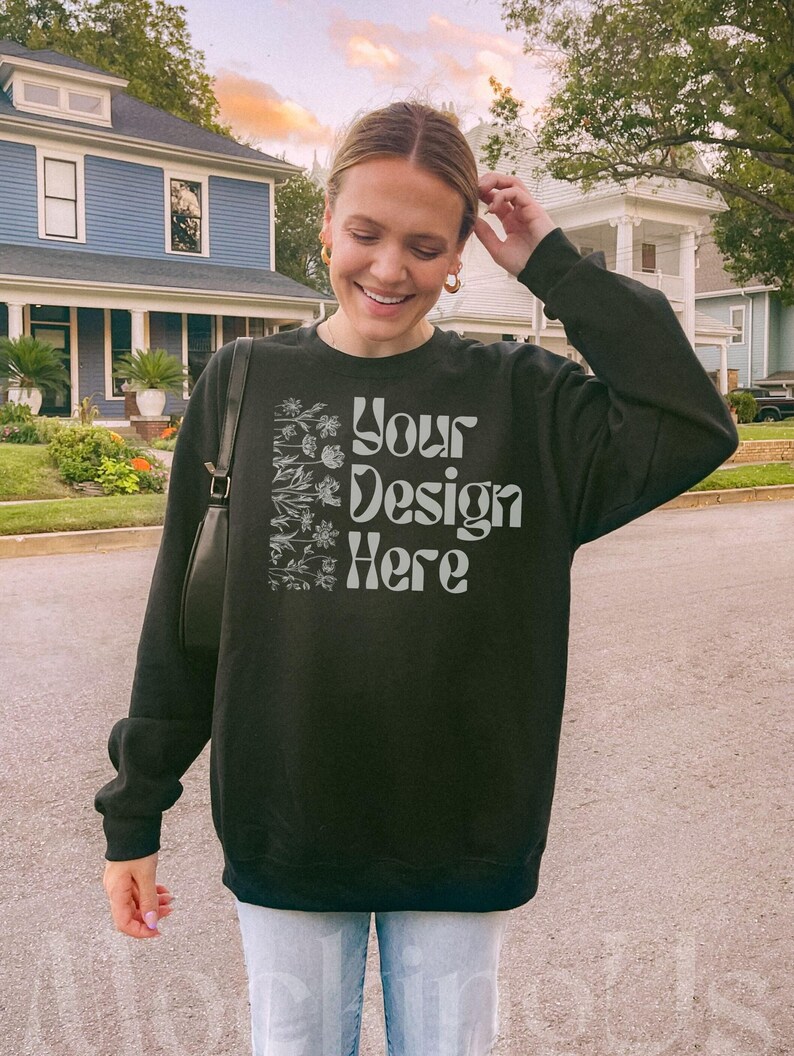 Black Gildan 18000 sweatshirt mockup. Model is showing front of the oversized crewneck. It is an outdoor lifestyle photo with a trendy Y2K aesthetic.