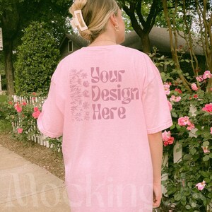 Real model wearing an oversized Blossom pink Comfort Colors 1717 t-shirt in a spring floral outdoor setting; size XL shown.