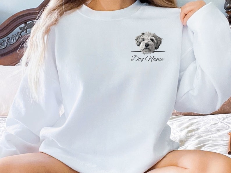 May include: White sweatshirt with a graphic of a dog's head peeking over a line with the text "Dog Name" underneath.