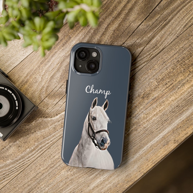 May include: A blue phone case featuring a white horse illustration and the word "Champ" printed on it.