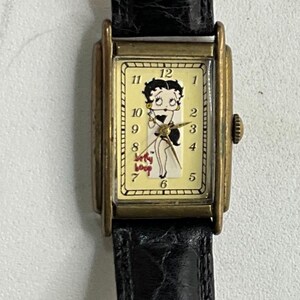 Peut inclure: Montre-bracelet vintage Betty Boop avec un bracelet en cuir noir et un bo&icirc;tier dor&eacute;. Le cadran de la montre pr&eacute;sente un graphisme Betty Boop et un fond cr&egrave;me. Une montre classique.