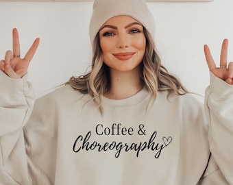 Op de afbeelding: Een beige sweatshirt met de tekst "Coffee & Choreography" in zwarte cursieve letters en een klein hartje.