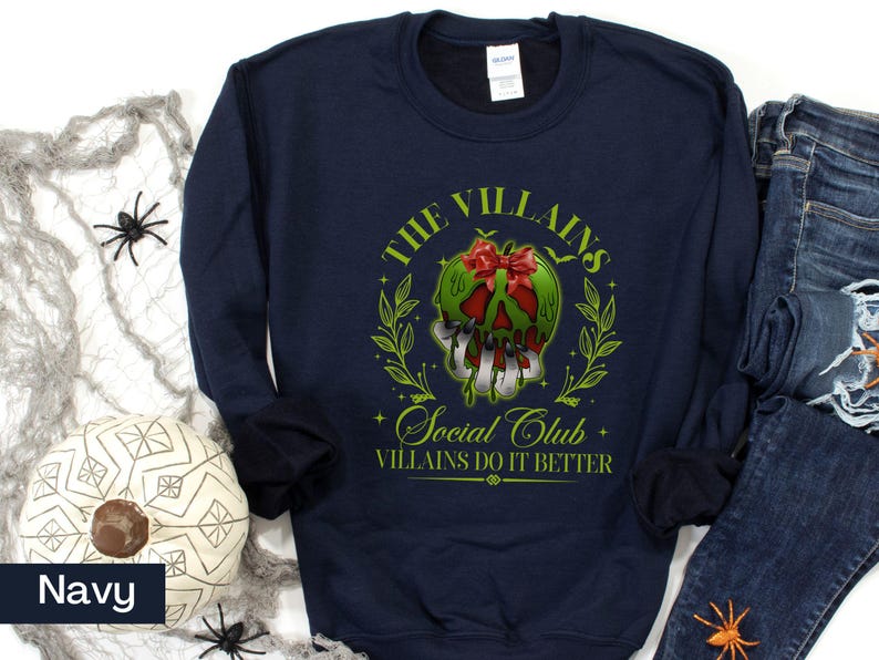 May include: Navy blue sweatshirt with a graphic featuring a green skull with a red bow, surrounded by a green wreath. Text reads "The Villains Social Club, Villains Do It Better."