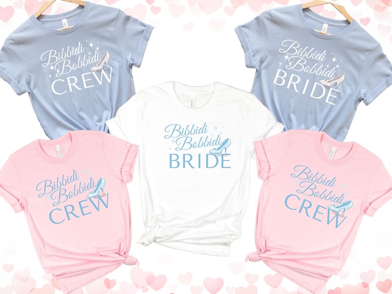 May include: Set of five t-shirts with a light blue and pink color scheme. The shirts feature the text "Bibbidi Bobbidi" with a Cinderella glass slipper graphic. Two shirts say "Crew" and two shirts say "Bride".