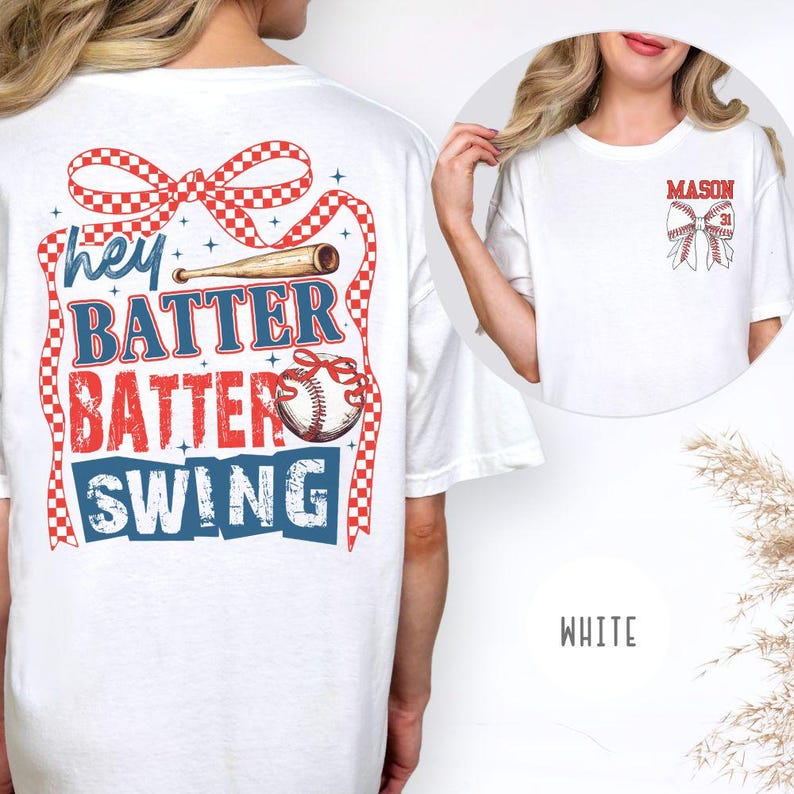 May include: White t-shirt with baseball-themed graphics. The back features the text "Hey Batter Batter Swing" in red and blue, with a baseball bat and bow design. The front pocket has a baseball bow and the name "MASON" in red.
