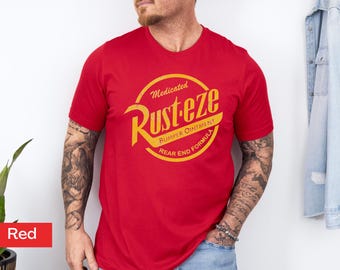 May include: A red crew neck t-shirt featuring a yellow and orange circular graphic with the text "Medicated Rust-eze Bumper Ointment Rear End Formula". The shirt is short-sleeved.
