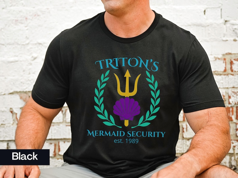 Pu&ograve; includere: T-shirt nero girocollo con la scritta "TRITON'S MERMAID SECURITY est. 1989". Il design presenta un tridente dorato, una conchiglia viola e una corona d'alloro verde acqua. La maglietta &egrave; in materiale morbido.