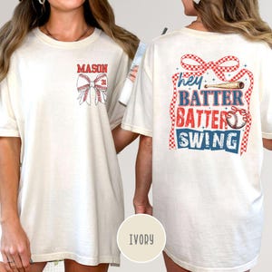 May include: Ivory-colored t-shirt with baseball-themed graphics. The front features the name "MASON" above a baseball bow with the number "31." The back displays "hey BATTER BATTER SWING" with baseball and ribbon details.