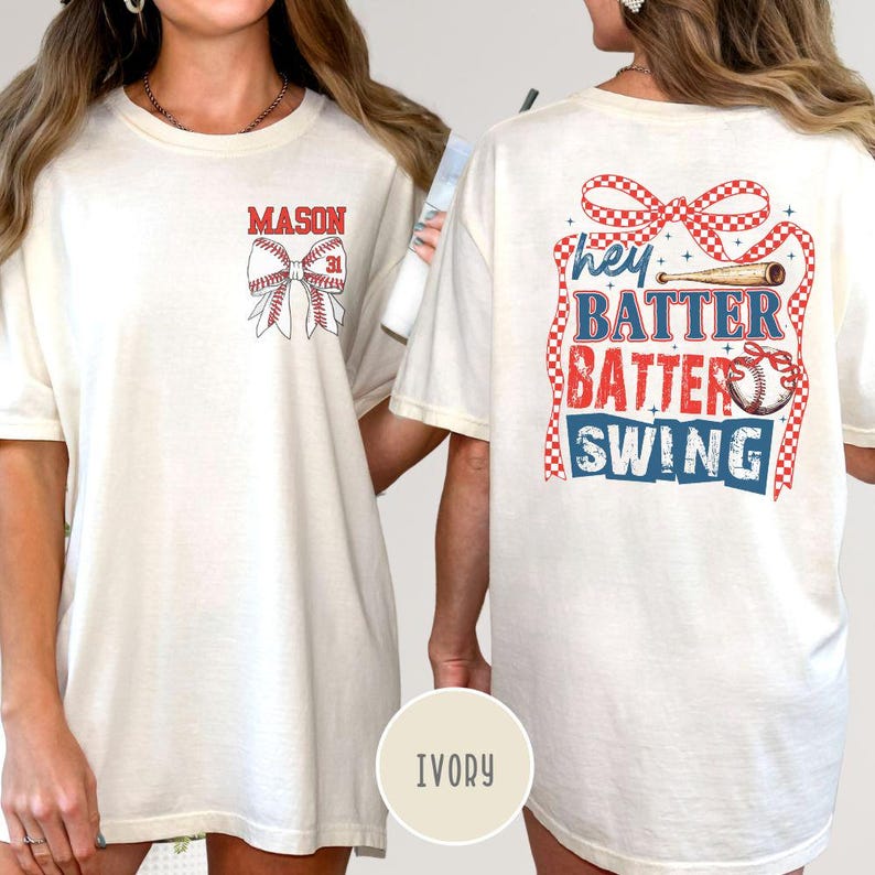 May include: Ivory-colored t-shirt with baseball-themed graphics. The front features the name "MASON" above a baseball bow with the number "31." The back displays "hey BATTER BATTER SWING" with baseball and ribbon details.