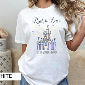 May include: White t-shirt with a graphic of Cinderella's castle and the text "Ready to Begin Let the Wonder Take Hold".
