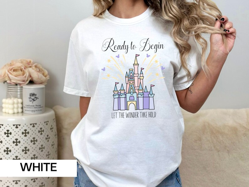 May include: White t-shirt with a graphic of Cinderella's castle and the text "Ready to Begin Let the Wonder Take Hold".