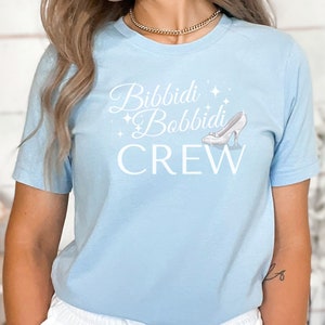 May include: Light blue t-shirt with a white graphic that says "Bibbidi Bobbidi Crew" with a glass slipper graphic.